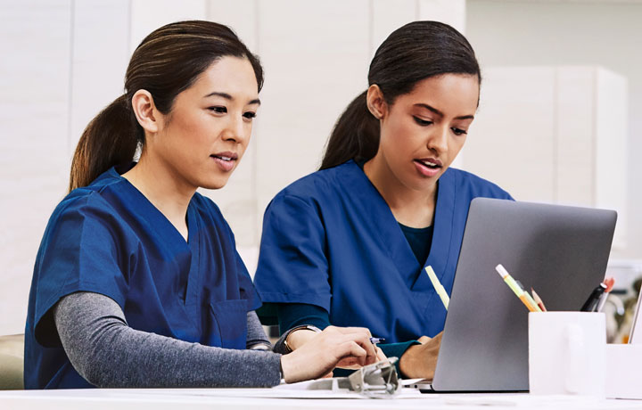 Two health care workers looking at a laptop