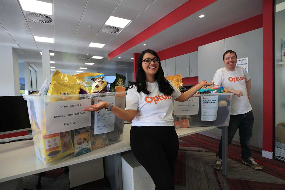 Two Optum colleagues next to a box of animal food and donations during a community engagement day 
